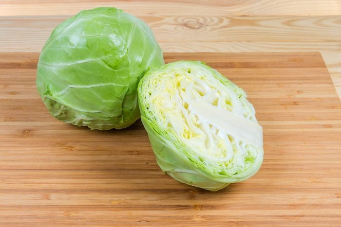 Whole and half of young cabbage head on cutting board
