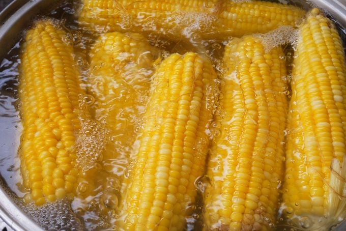 Yellow corn is boiled in a pot