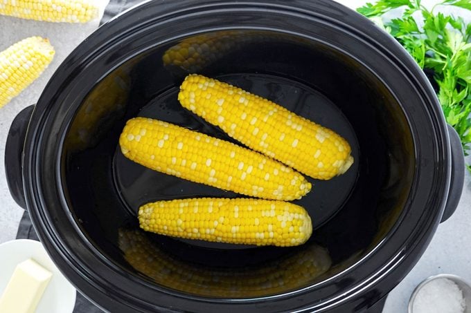 two ears of corn in a pot being boiled