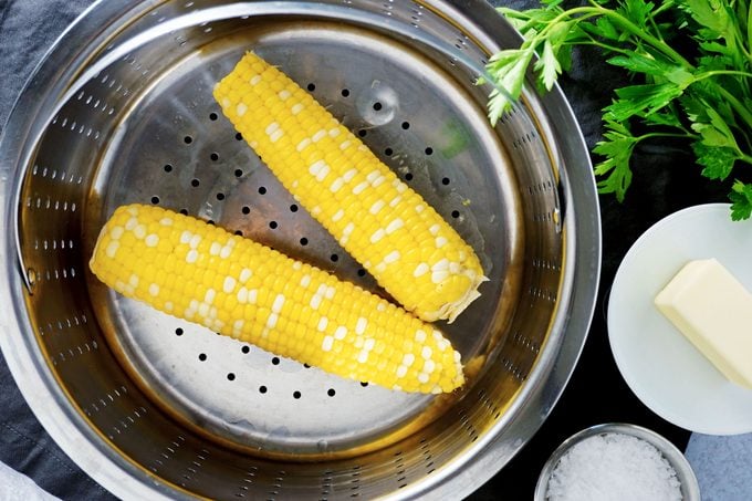 two ears of corn in a steam basket